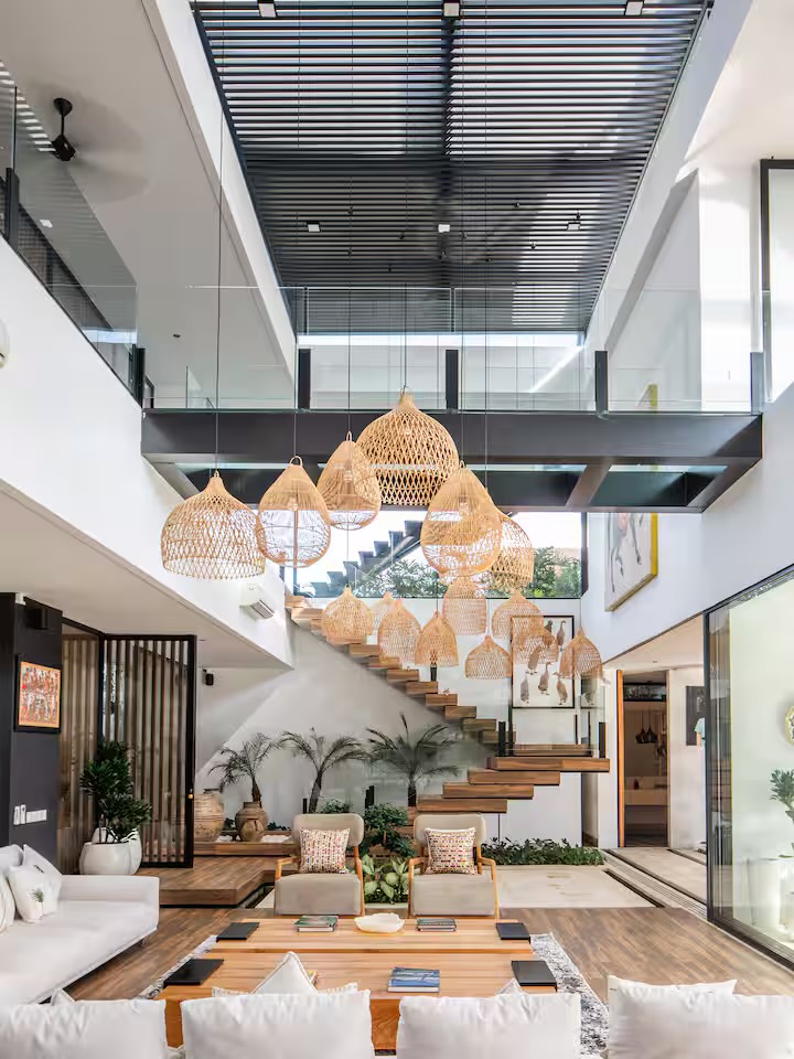 The full-height atrium with a cluster of rattan pendants above the floating timber staircase